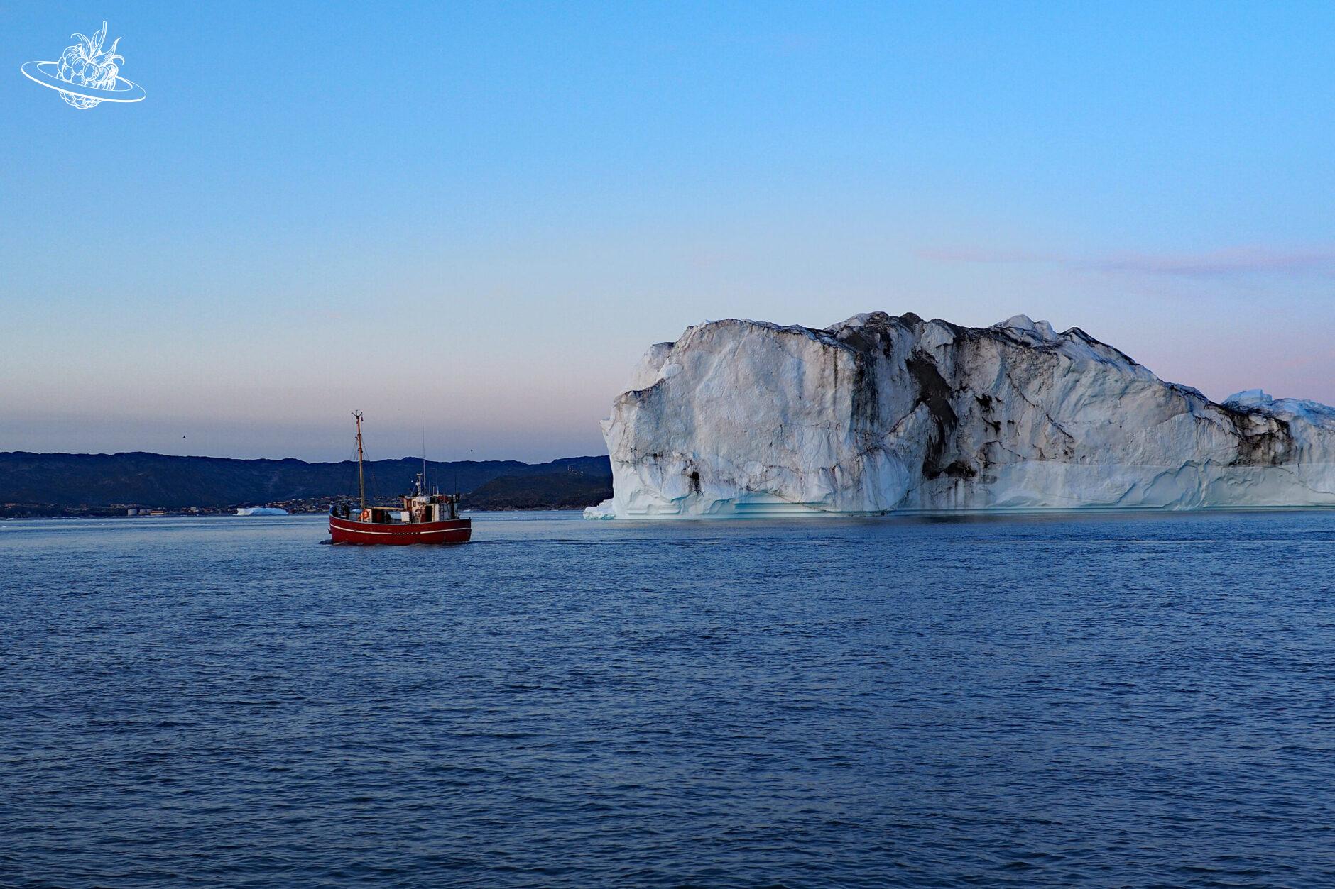 rotes Boot in der nähe von einem grossen Eisberg