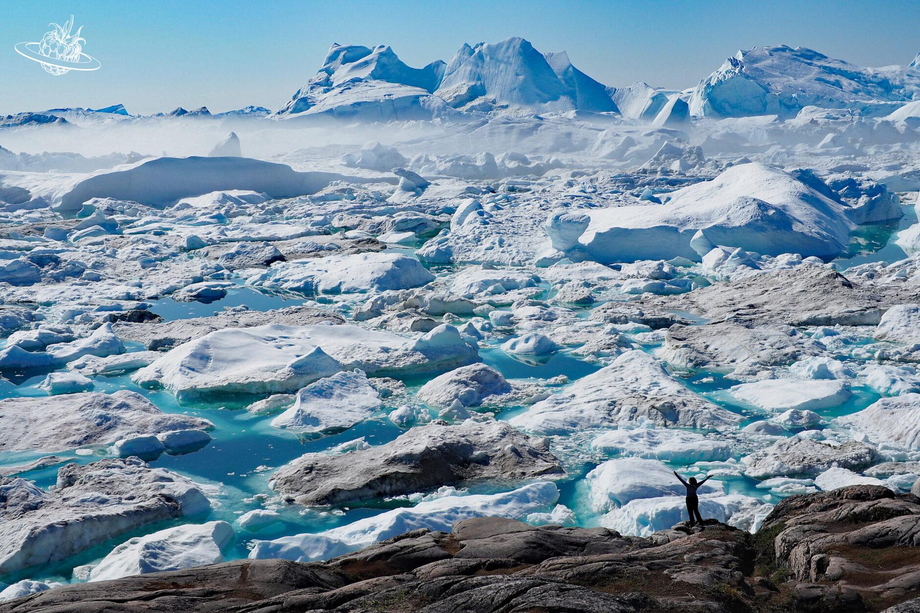 Frau vor riesiger Eisbergschicht in Ilulissat
