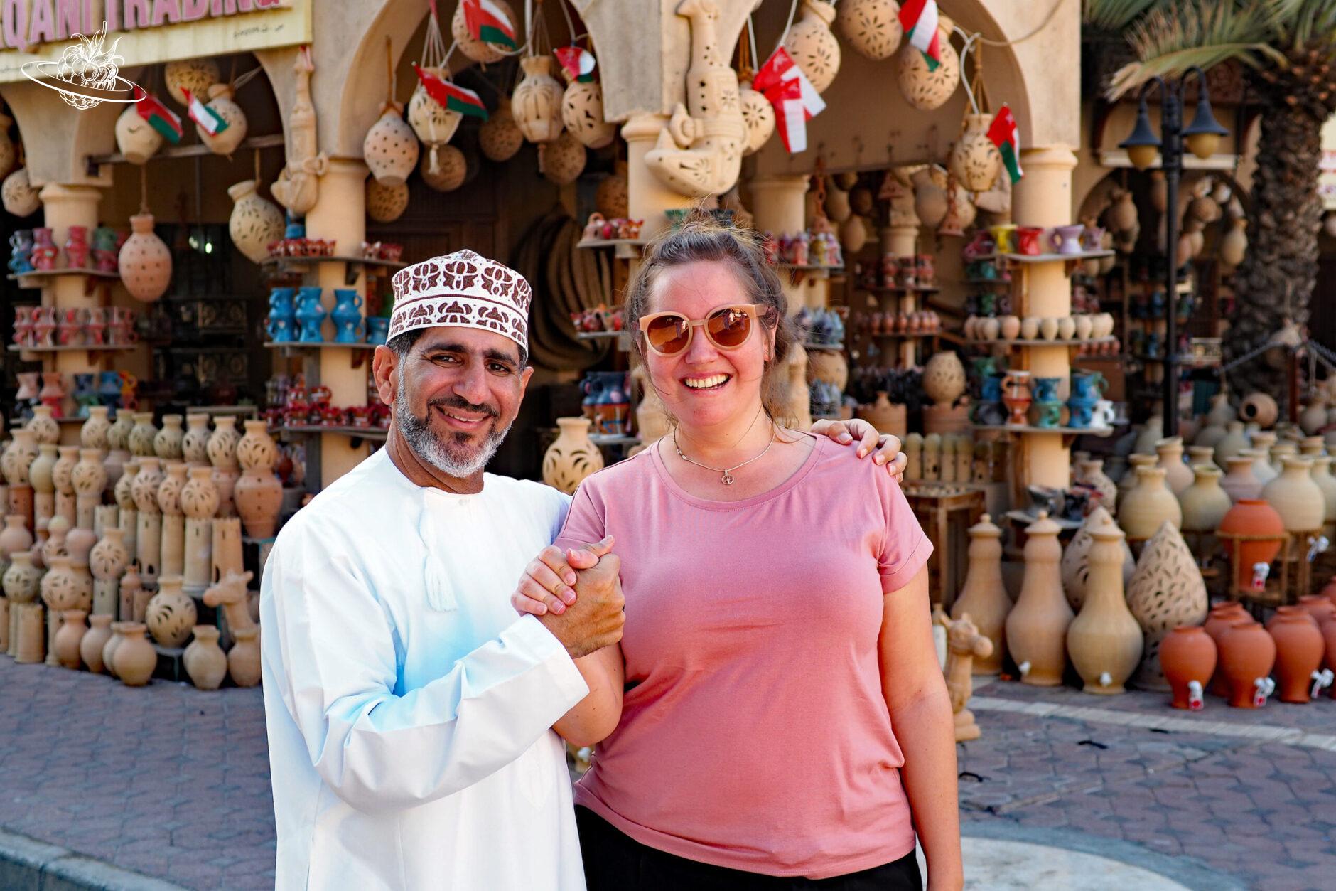 Westliche Frau mit Omani vor einem Souvenirladen