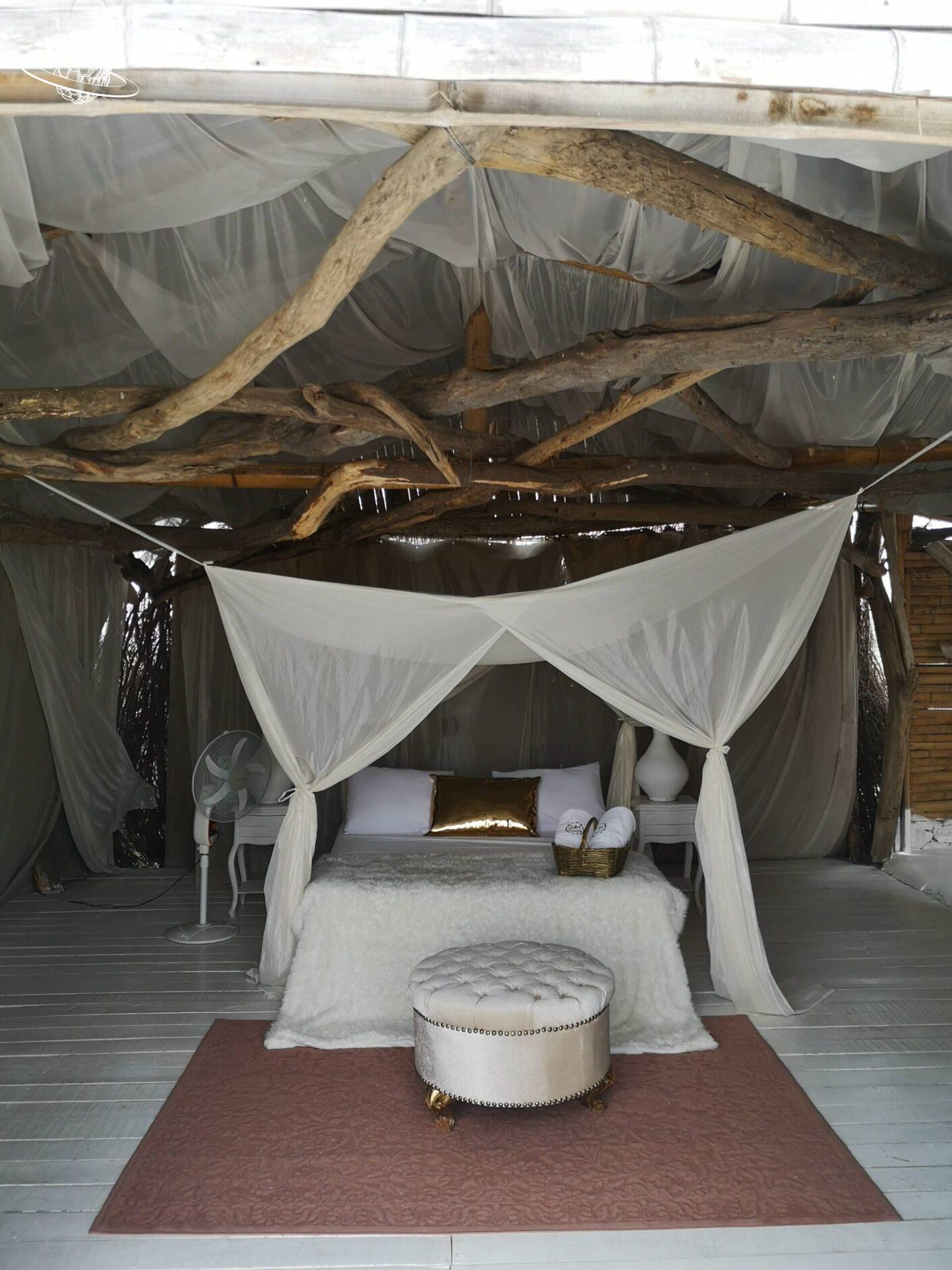 Bett mit Teppich und Dach aus Holzästen