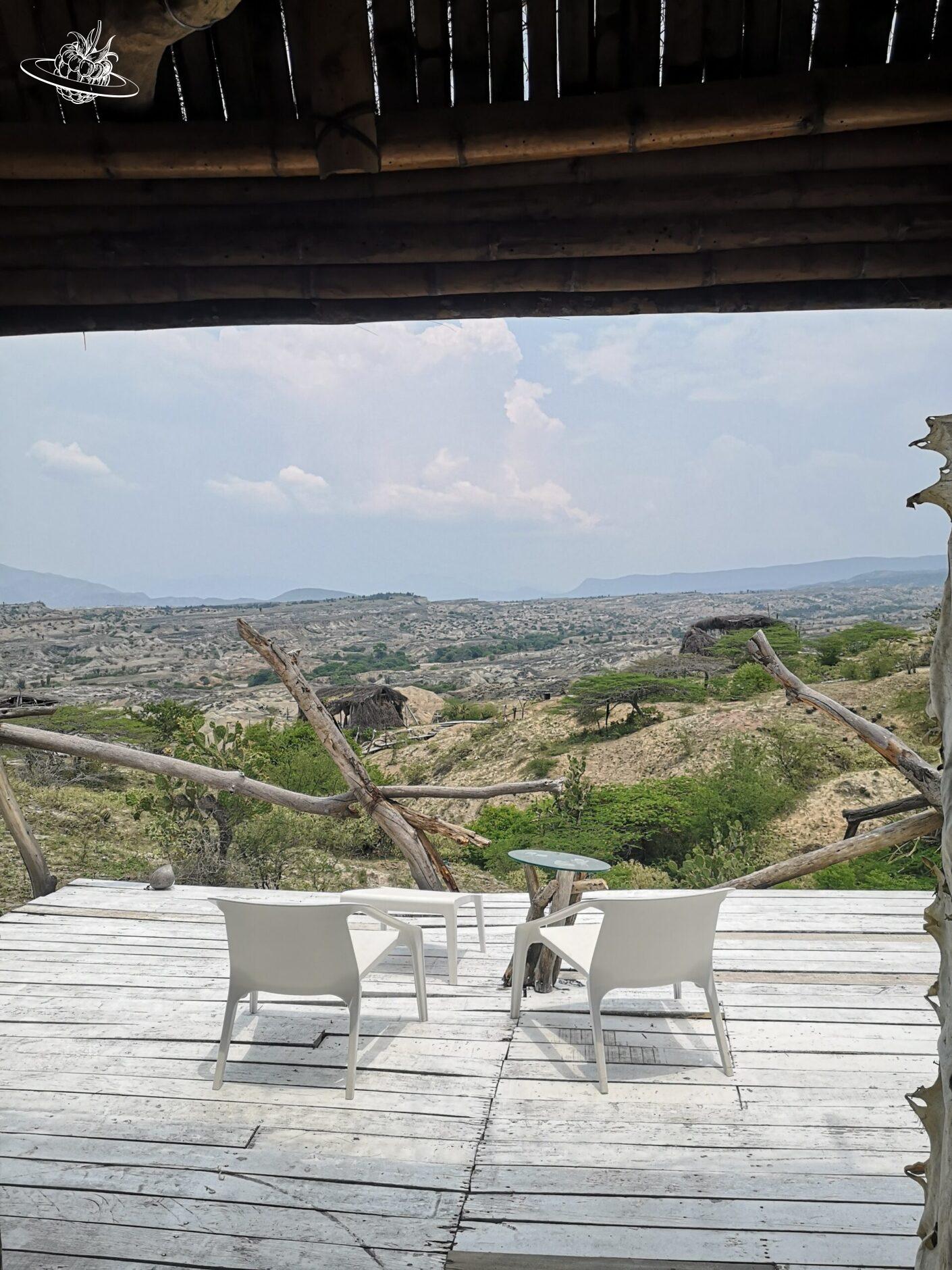 Terrasse mit zwei weissen Liegestühlen und Blick in die Wüste