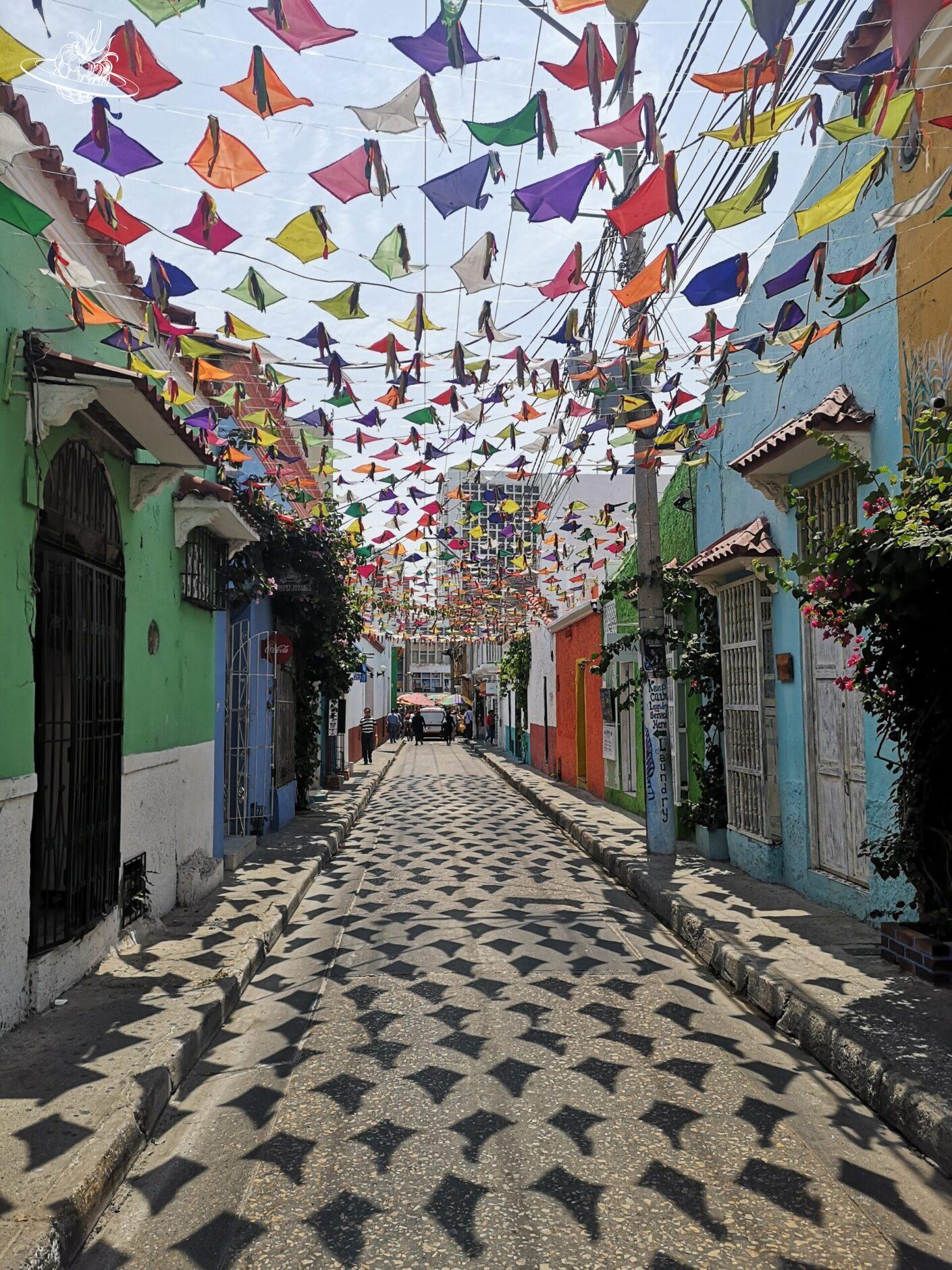 Gasse mit bunten Häusern und vielen kleinen Flaggen im Himmel