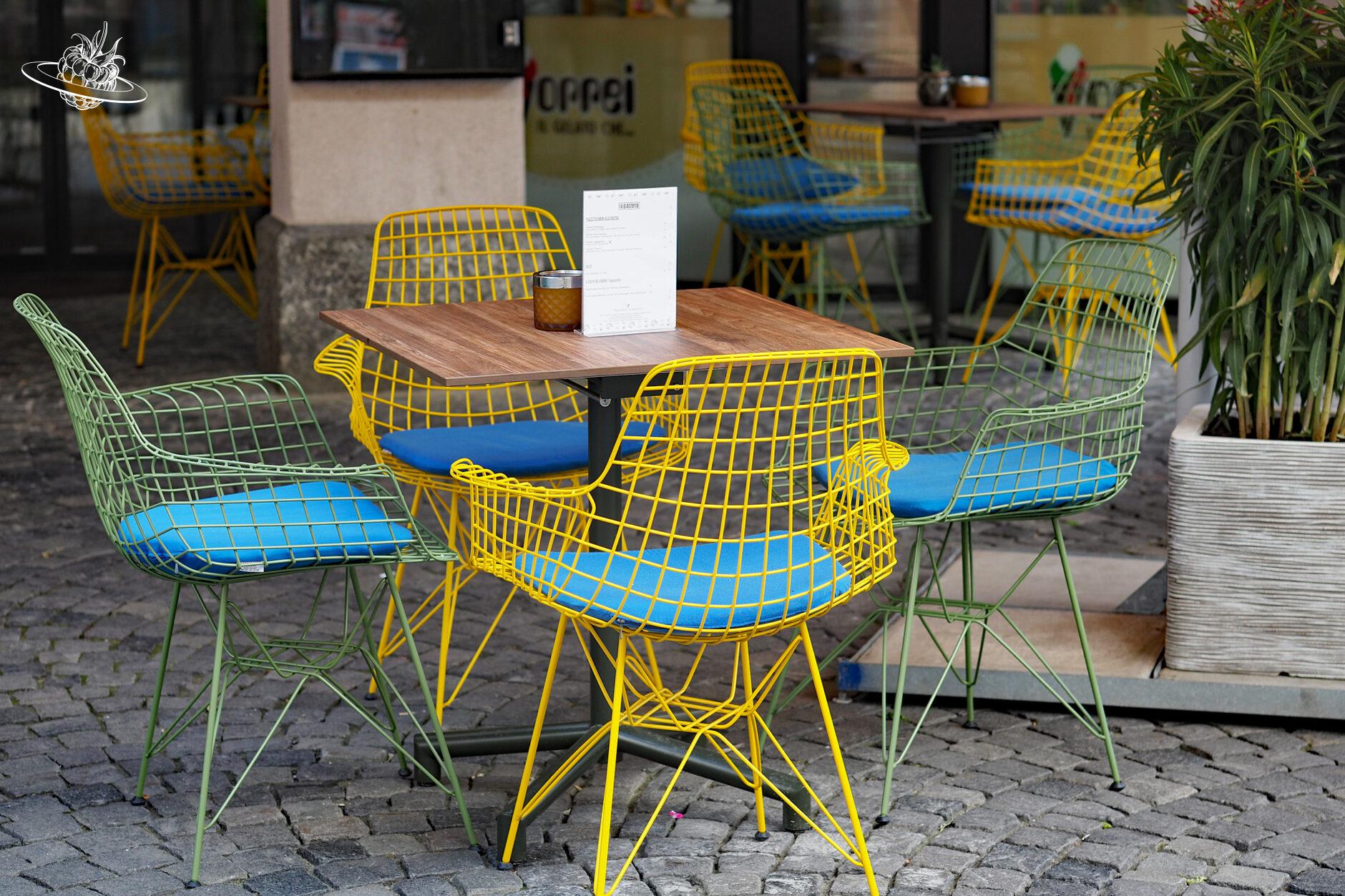Tisch mit farbigen Stühlen im Freien vor dem Restaurant