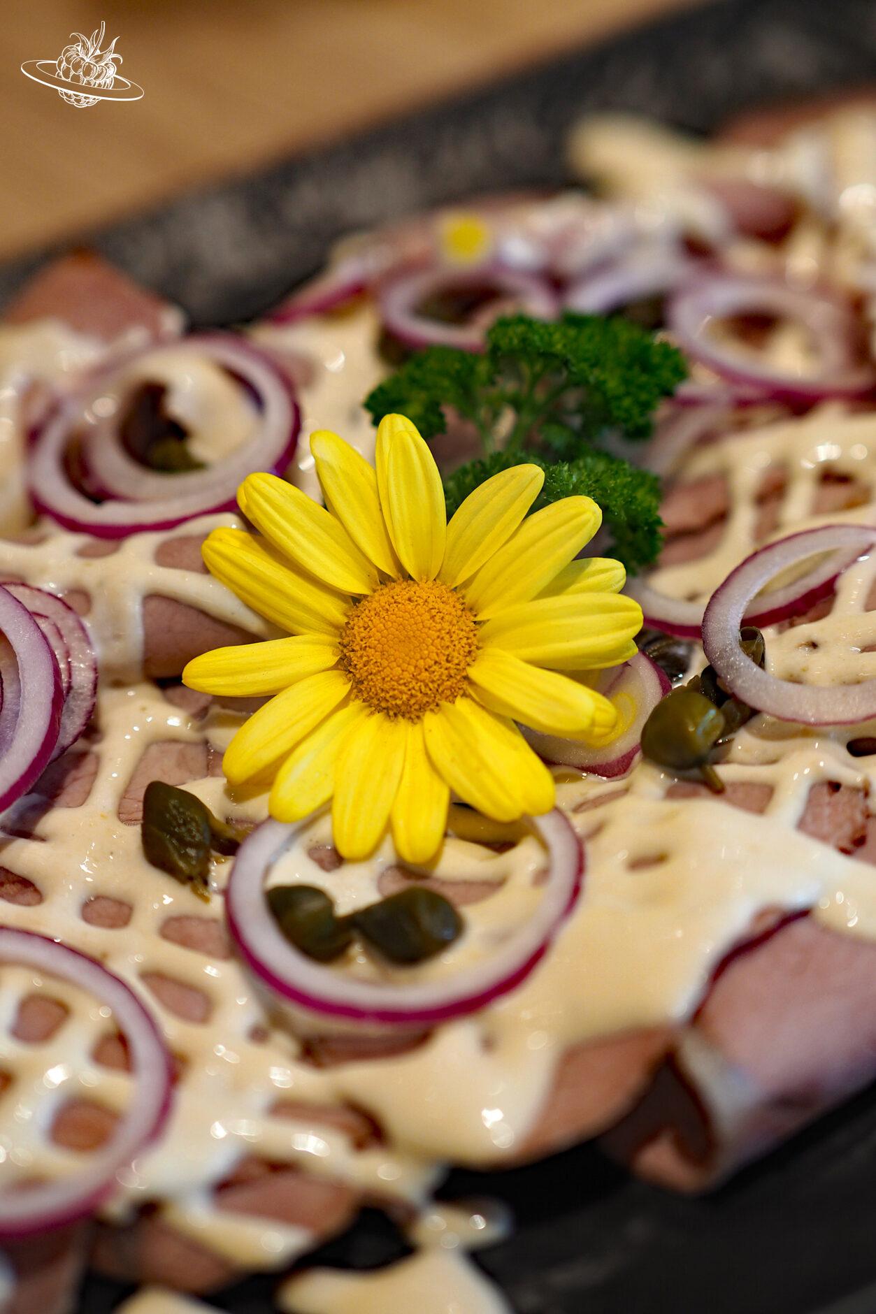 Mit einer gelben Blume dekoriertes Vitello Tonnato