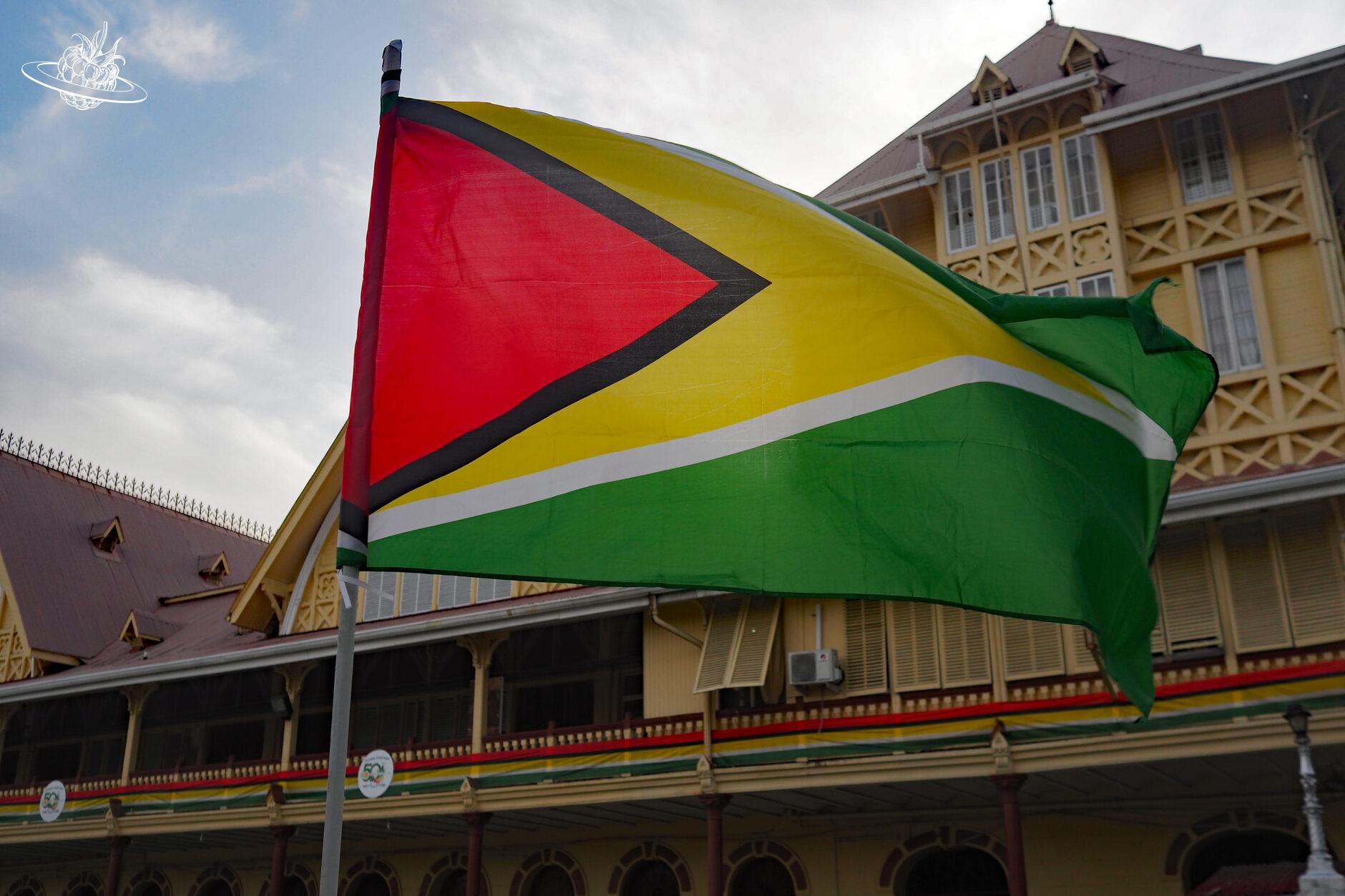 Guyana Flagge vor Kolonialgebäude
