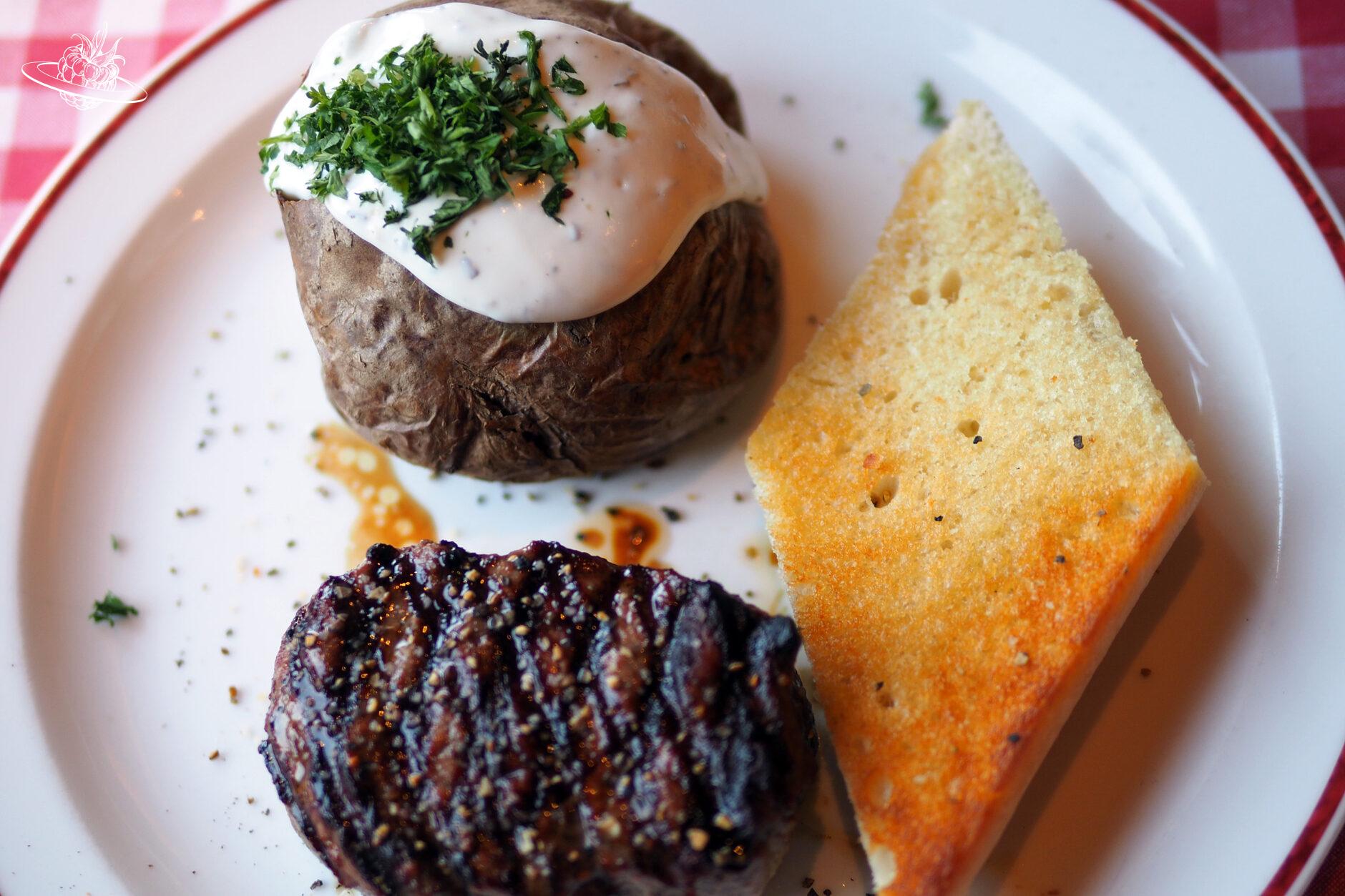Fleisch, gebackene Kartoffel mit Sauerrahm und Knoblauchbrot