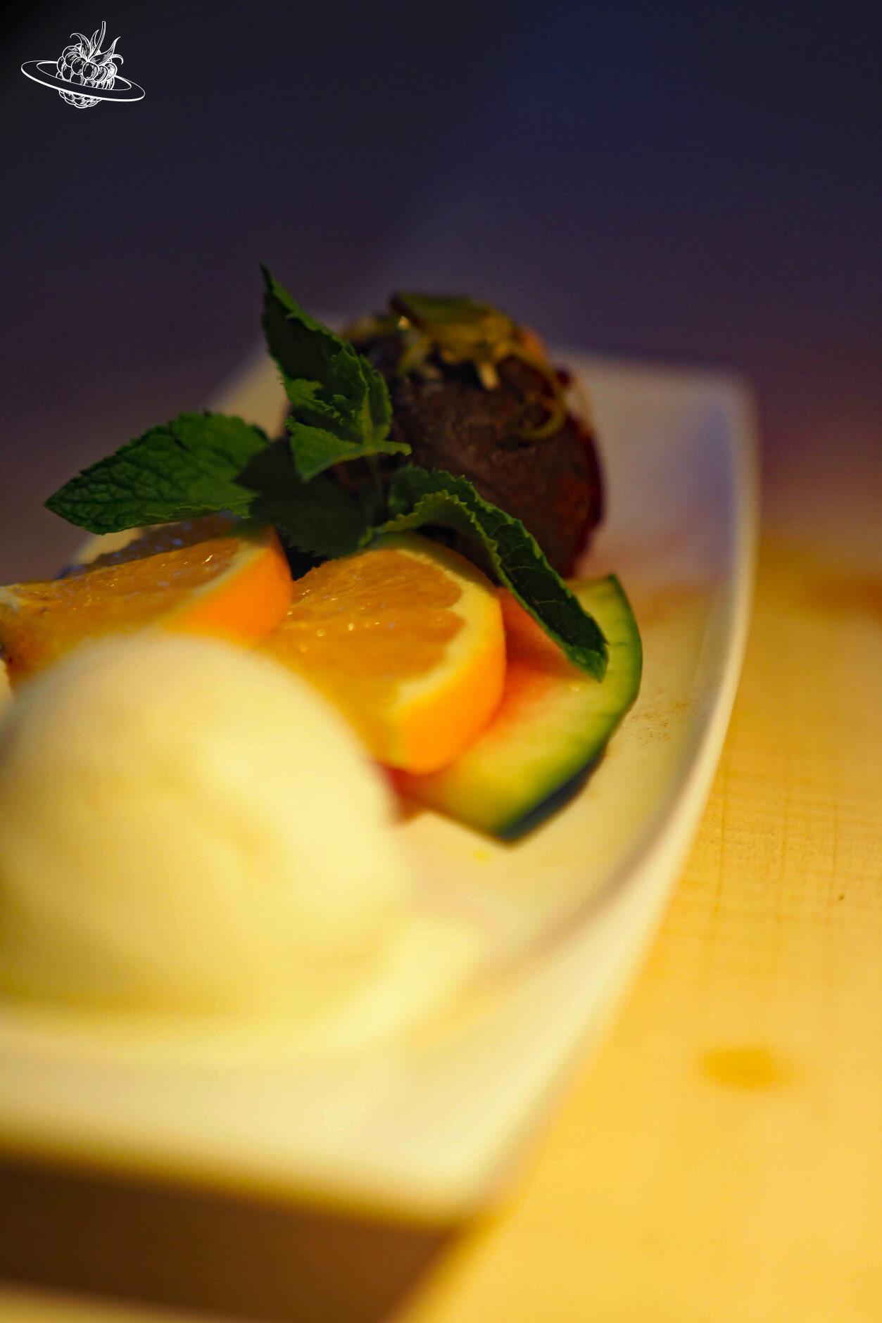 Teller mit Sauerrahmglace, Orangen und einer Kugel Schokoladen Ganache