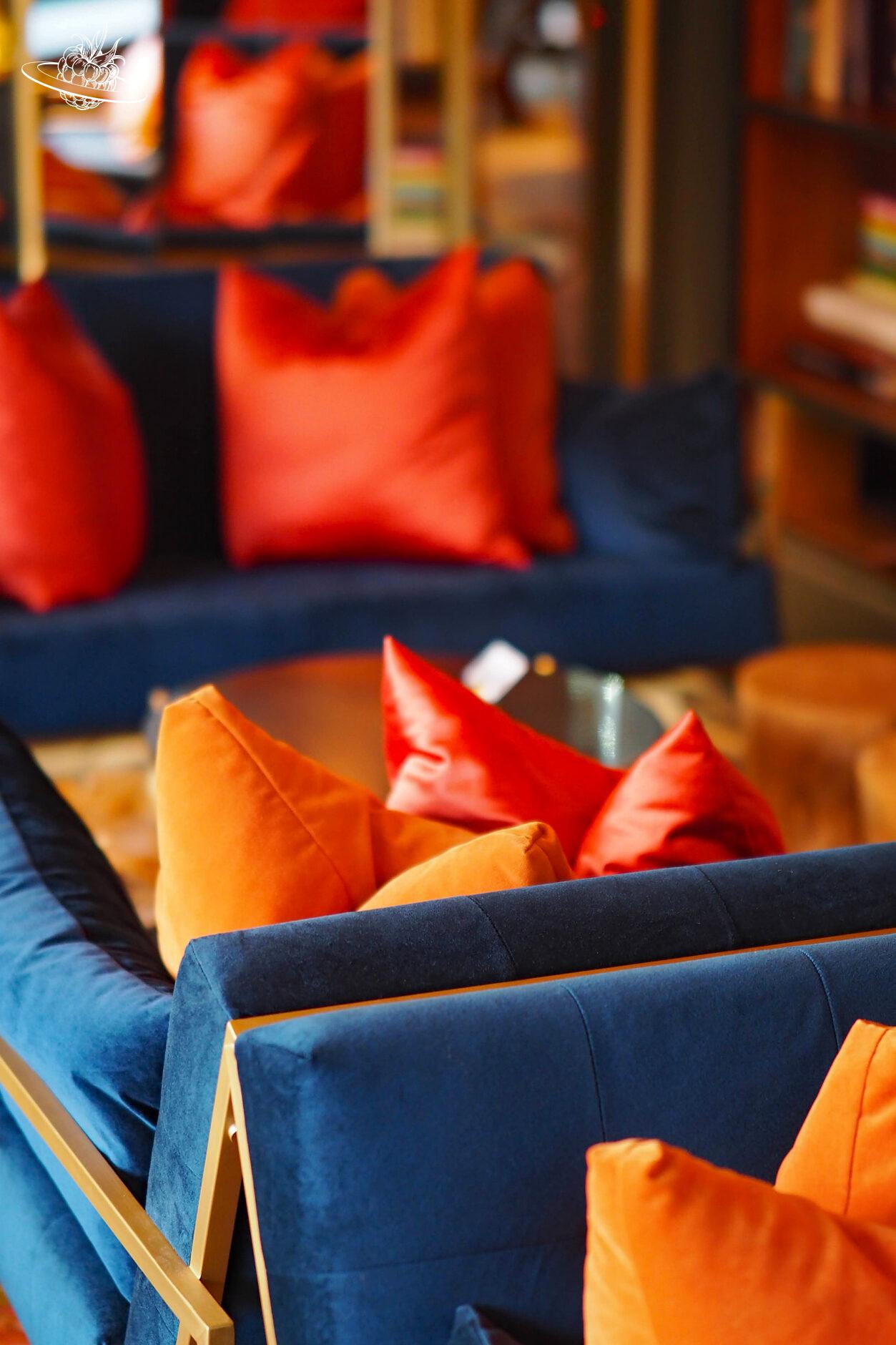 Blaue Sofas mit roten und orangen Kissen