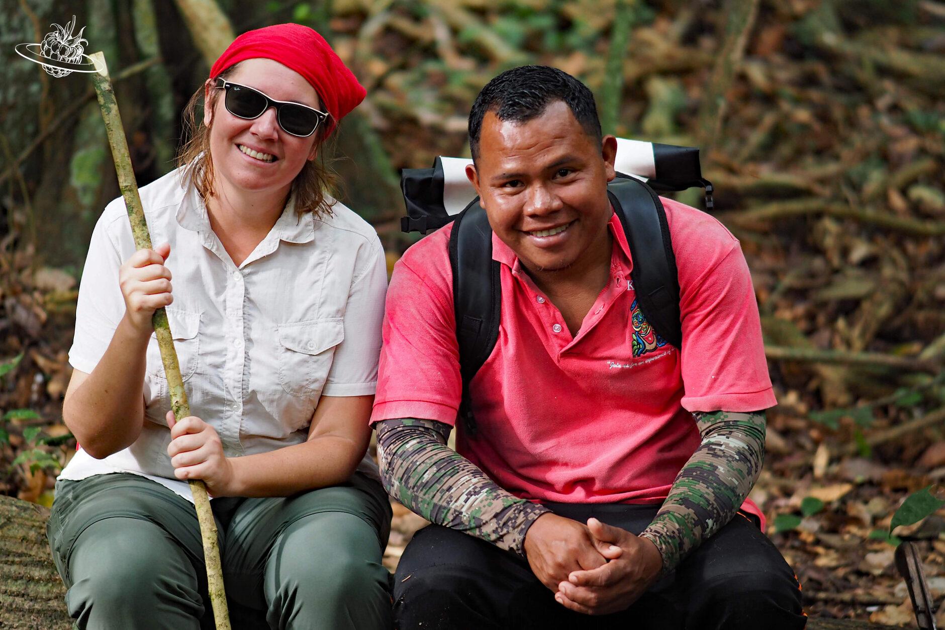 Andrea und unser Guide Orlando sitzen auf einem Baumstamm im Regenwald