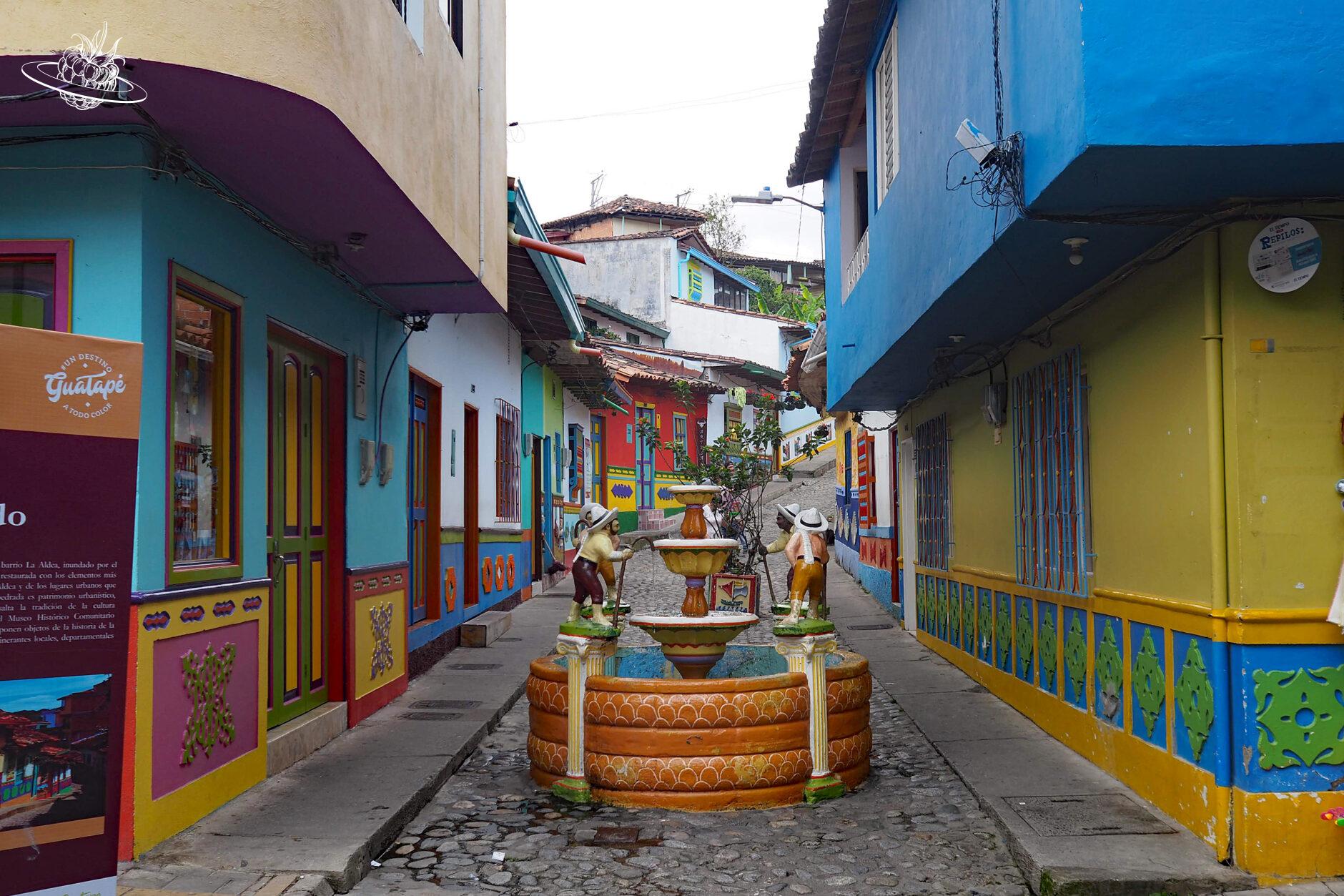 Gasse mit farbigen Häusern und einem dekorierten Bunnen in der Mitte