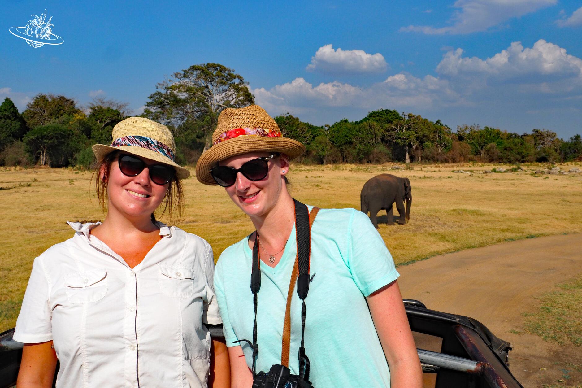 zwei Frauen und im hintergrund zwei elefanten