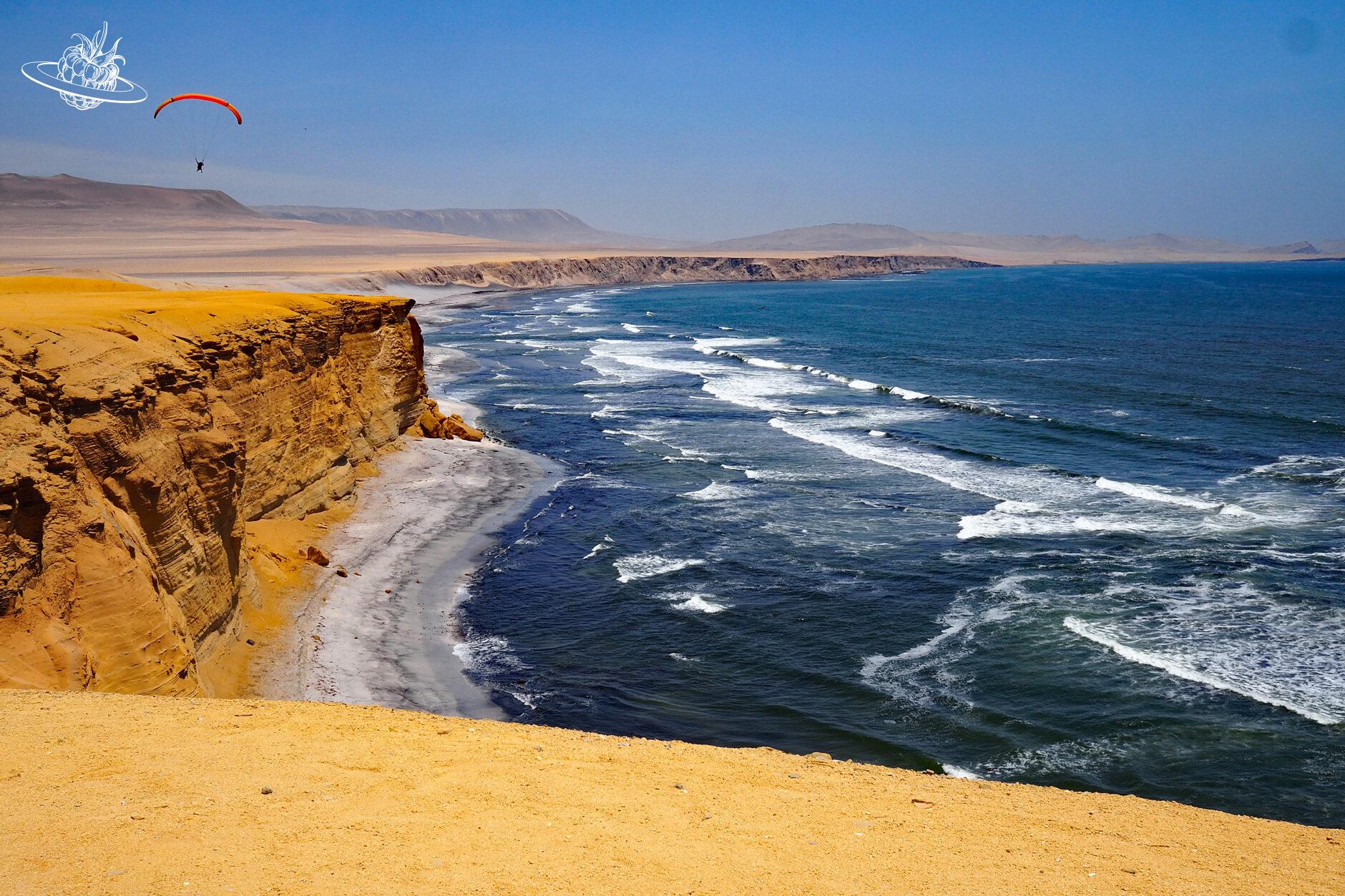Meer mit steilen Klippen und einem Gleitschirmflieger