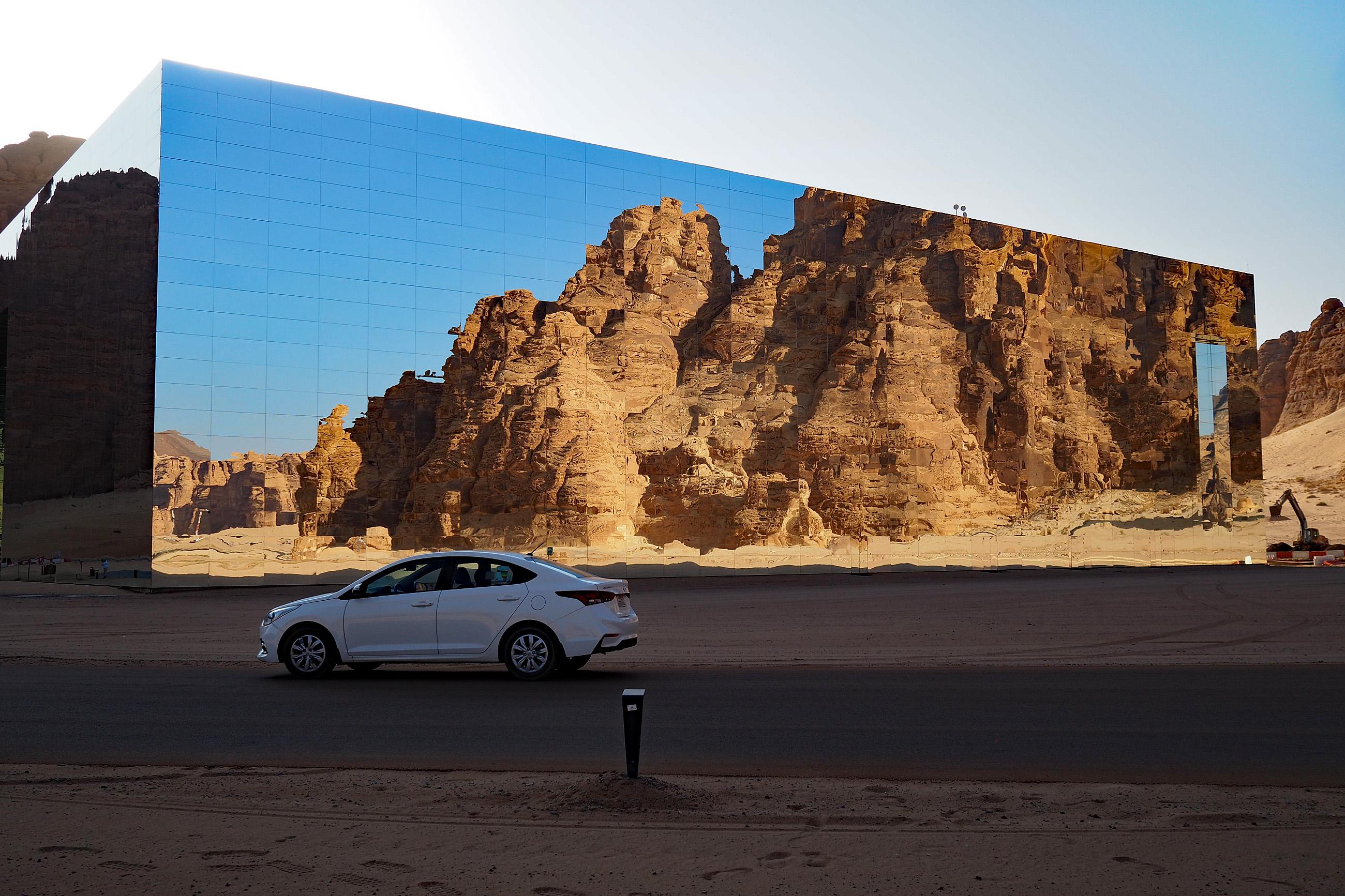 Auto vor Spiegelhaus, welches die Wüste spiegelt