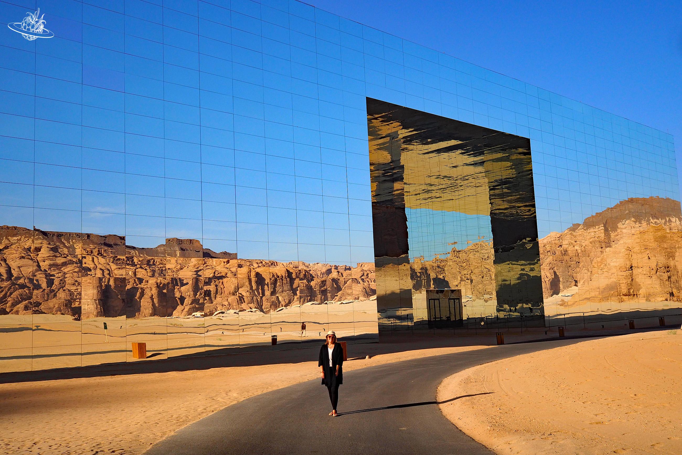 Frau vor Spiegelgebäude in der Wüste
