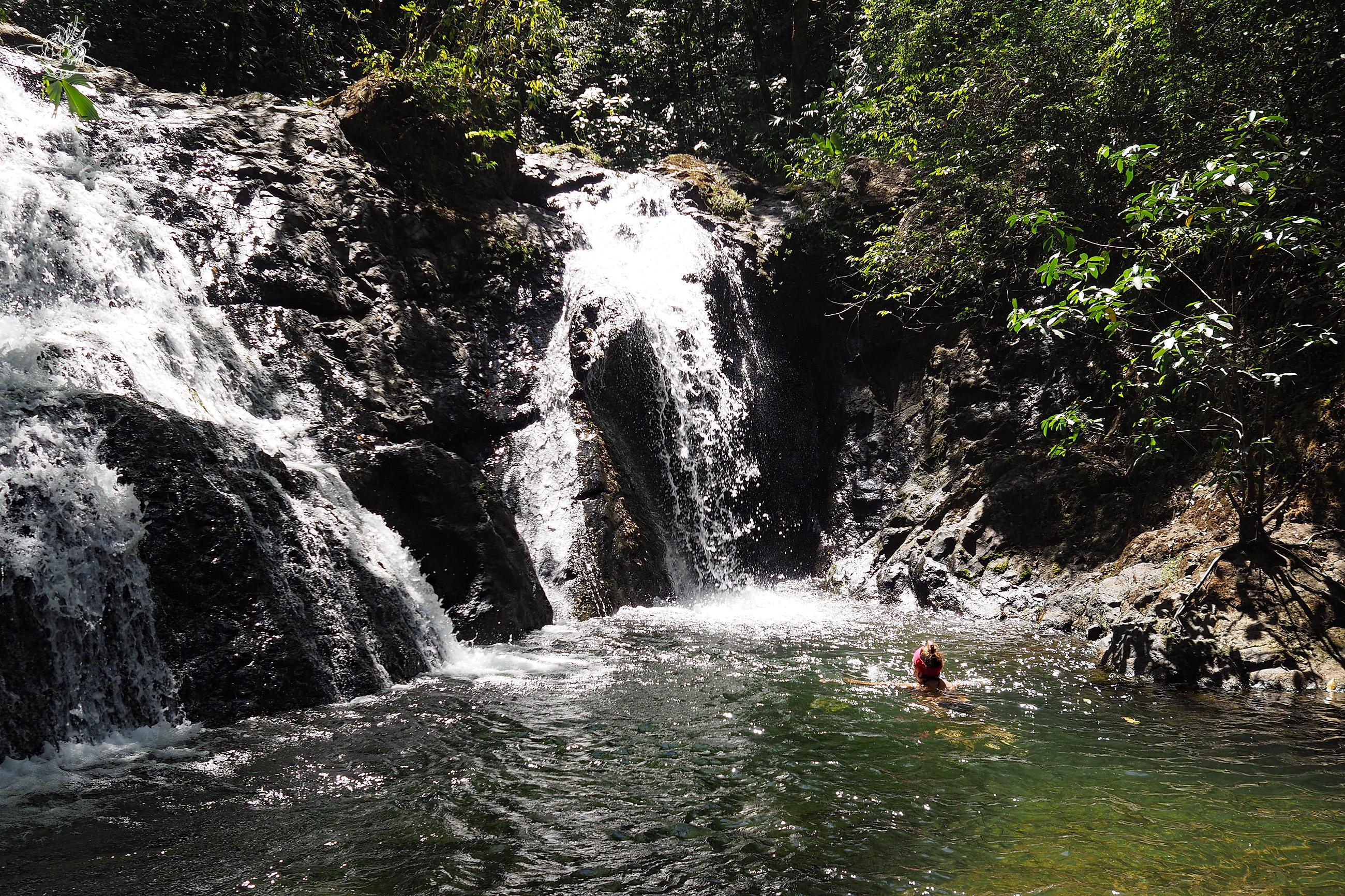 Frau badet im Wasserfall