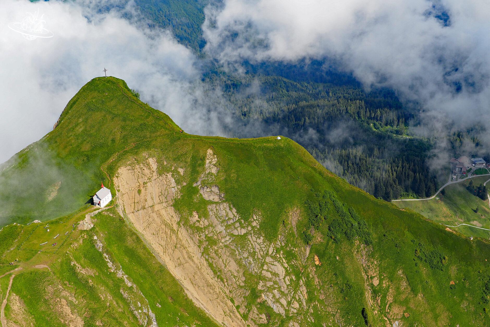 Aussicht auf einen steilen Berg mit Kirche und Kreuz