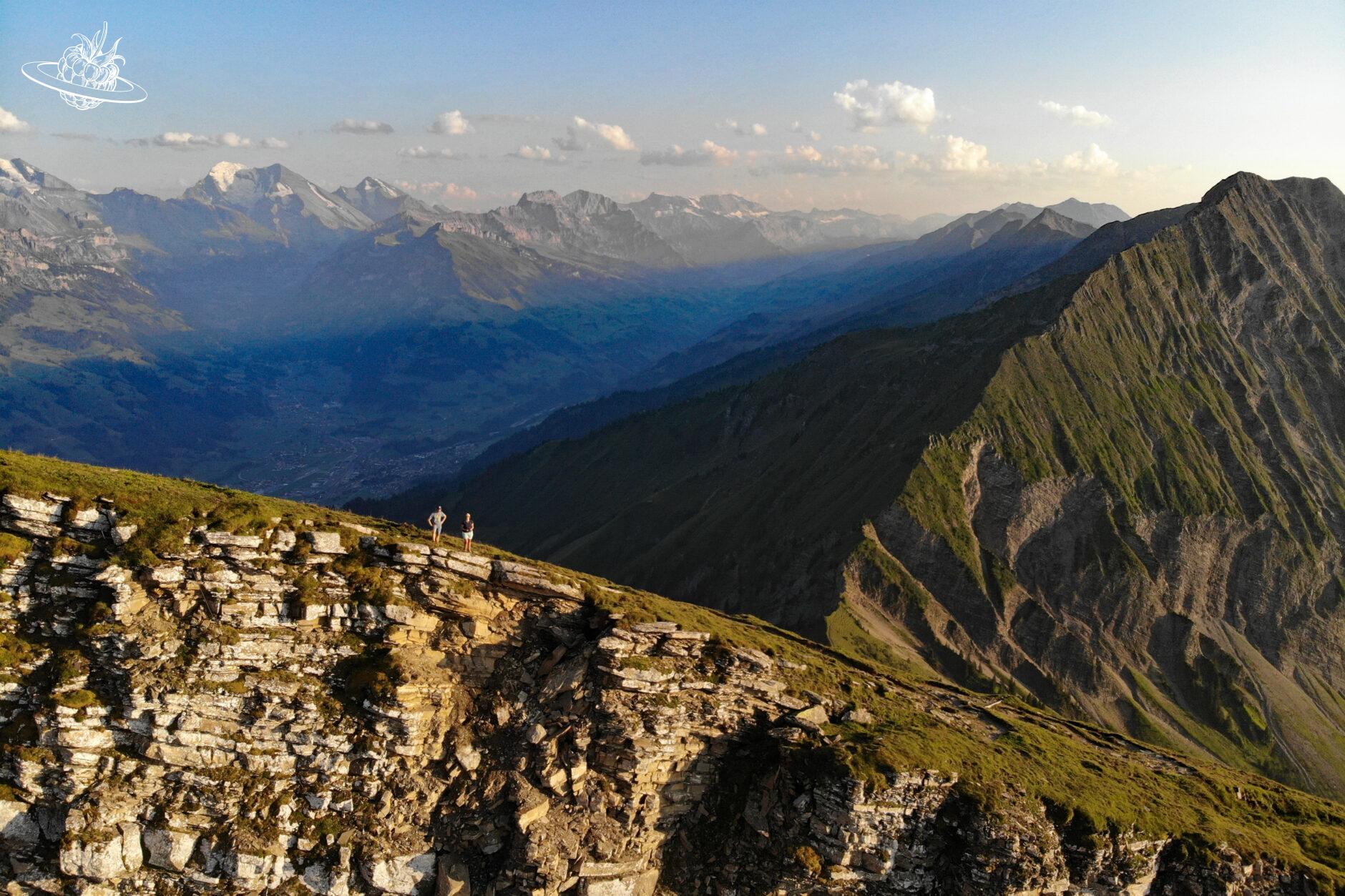 Päärchen auf Bergkante und im Hintergrund ein Bergtal