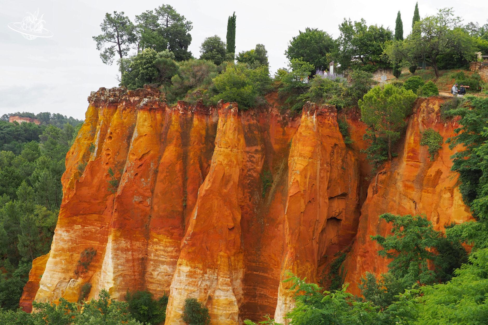 orange felswand inmitten von grünen bäumen