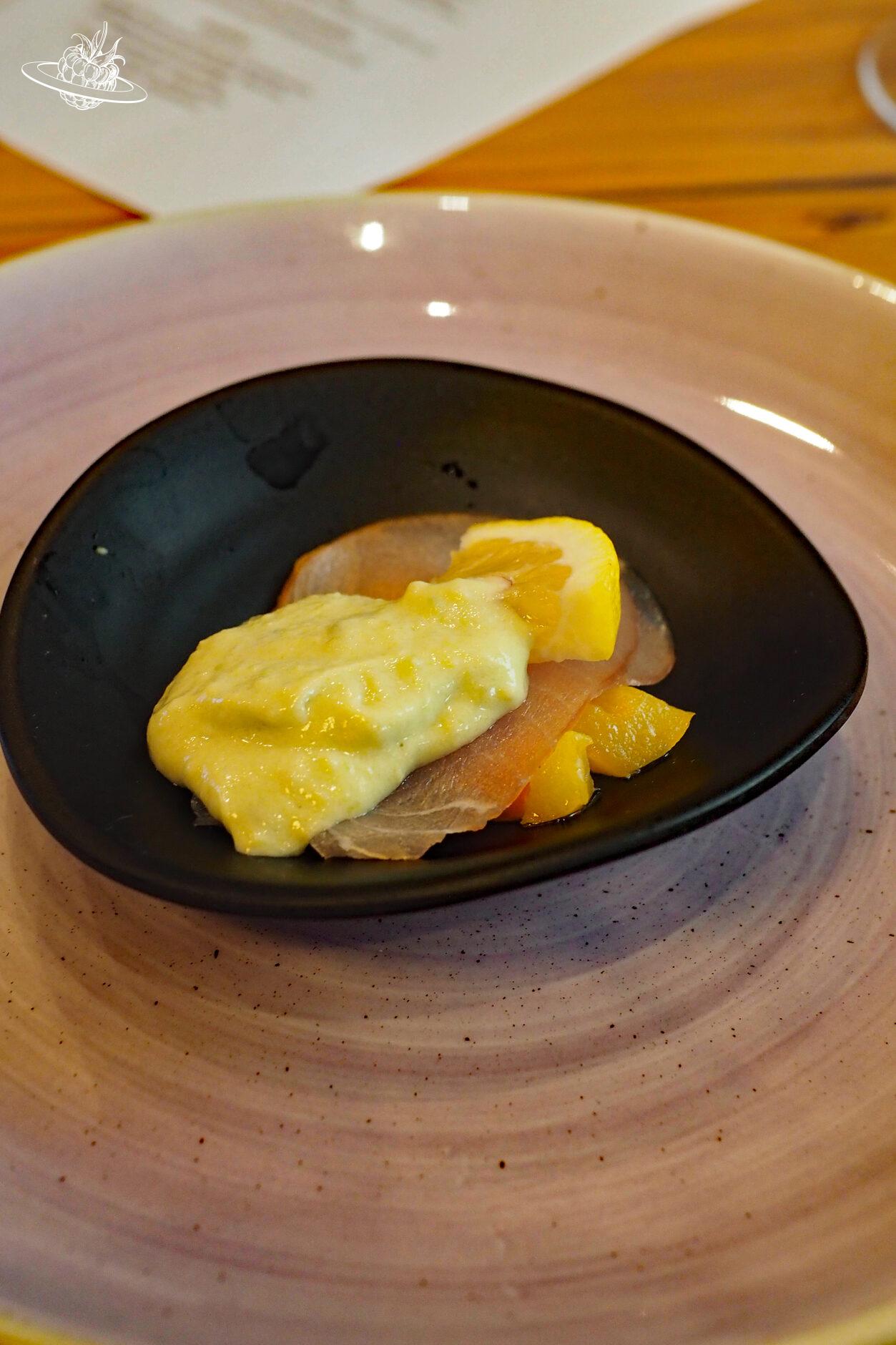 Schwarze Schale mit Vorspeise aus Lachts und einer gelben Sauce