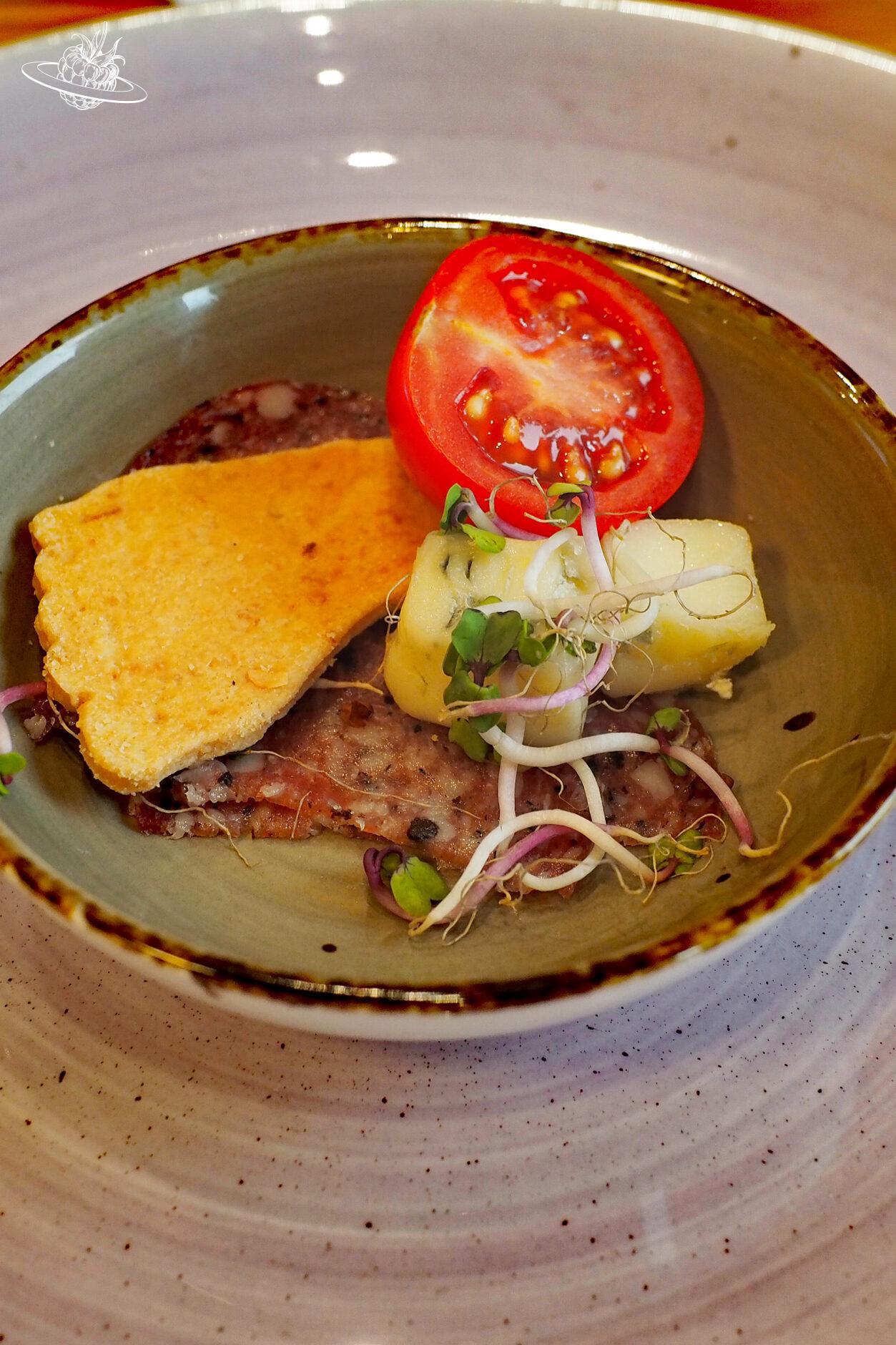 Schälchen mit Vorspeise aus Salami, Käse und einer halbierten Tomate