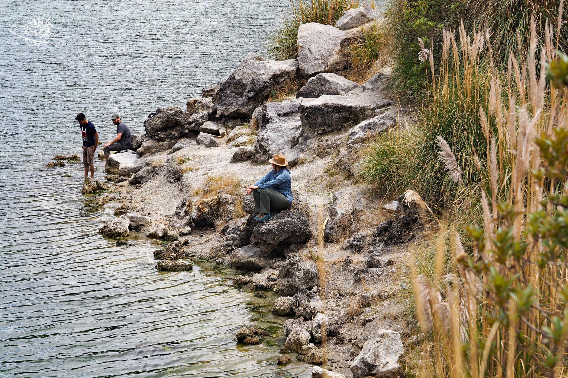 Frau sitzt am Ufer vom Kratersee