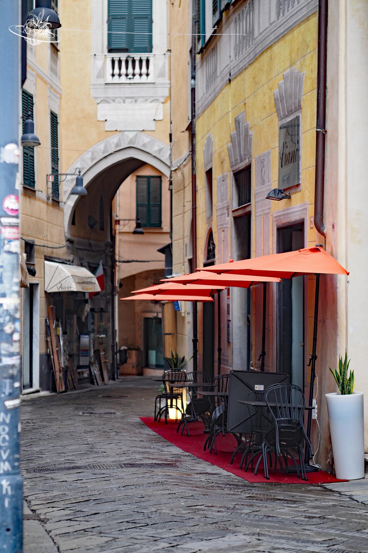 Enge Gasse mit roten Sonnenschirmen vor einem Restaurant