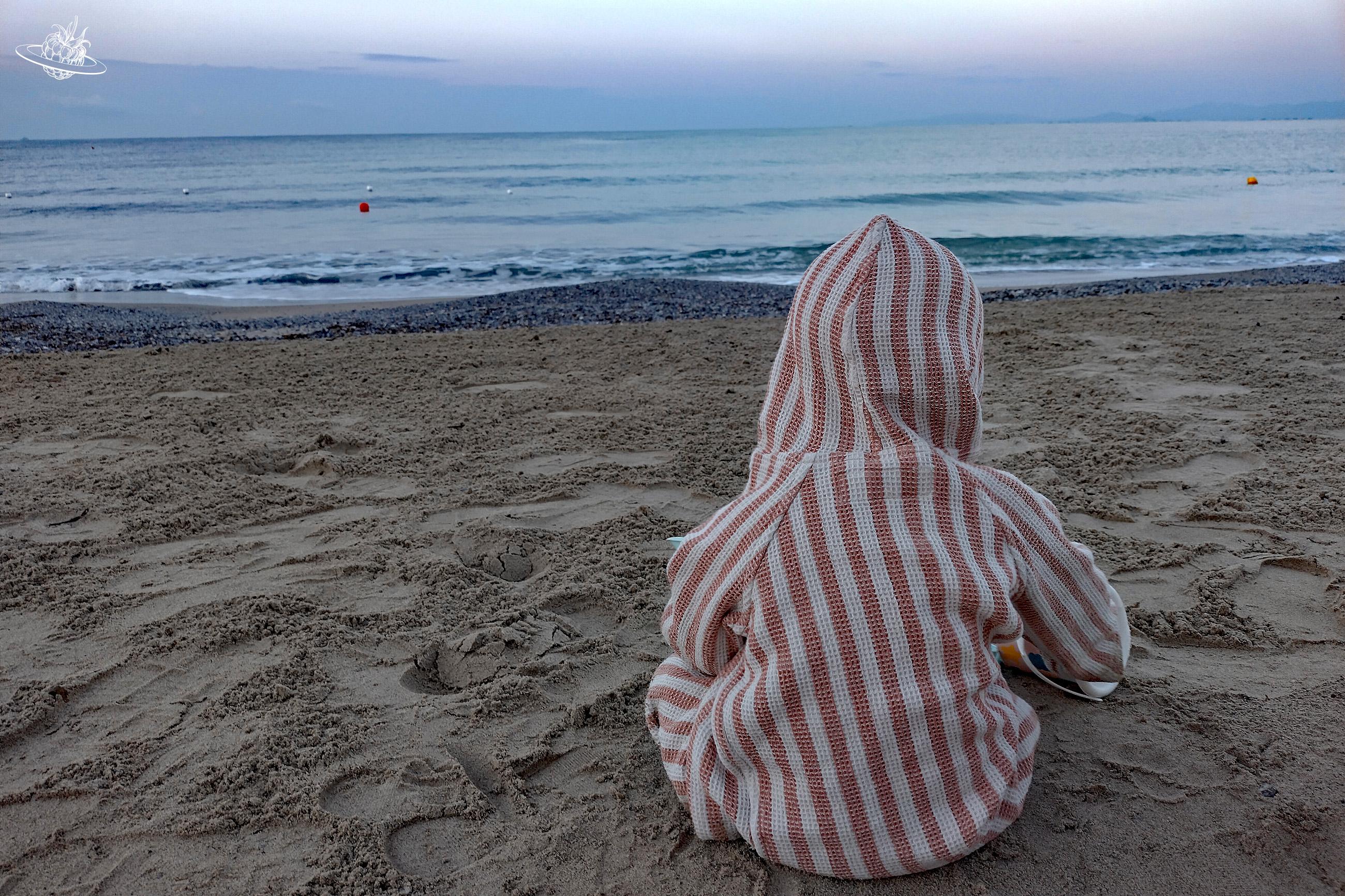 Kleines Kind sitzt am Strand