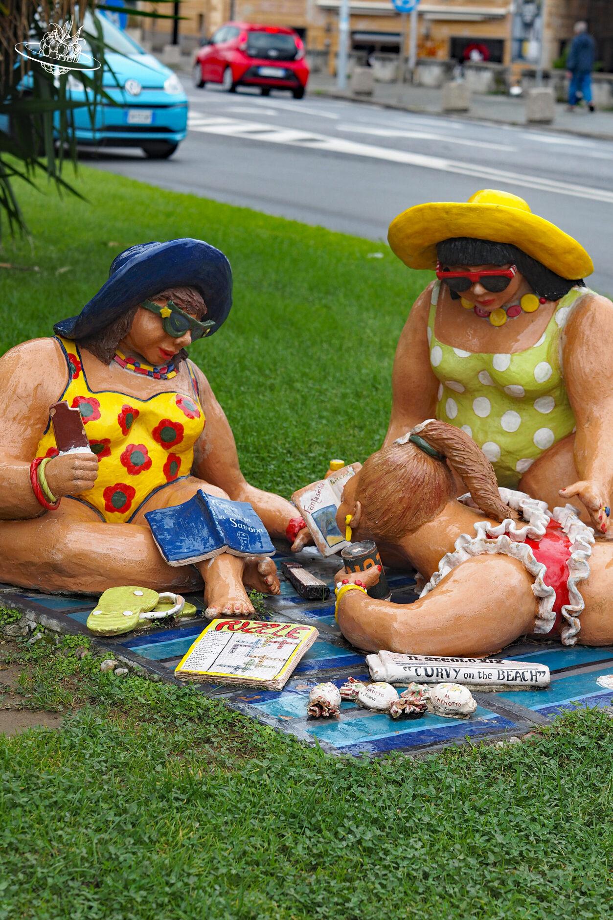 Kunstinstallation mit drei Frauen, welche auf einer Wiese sitzen