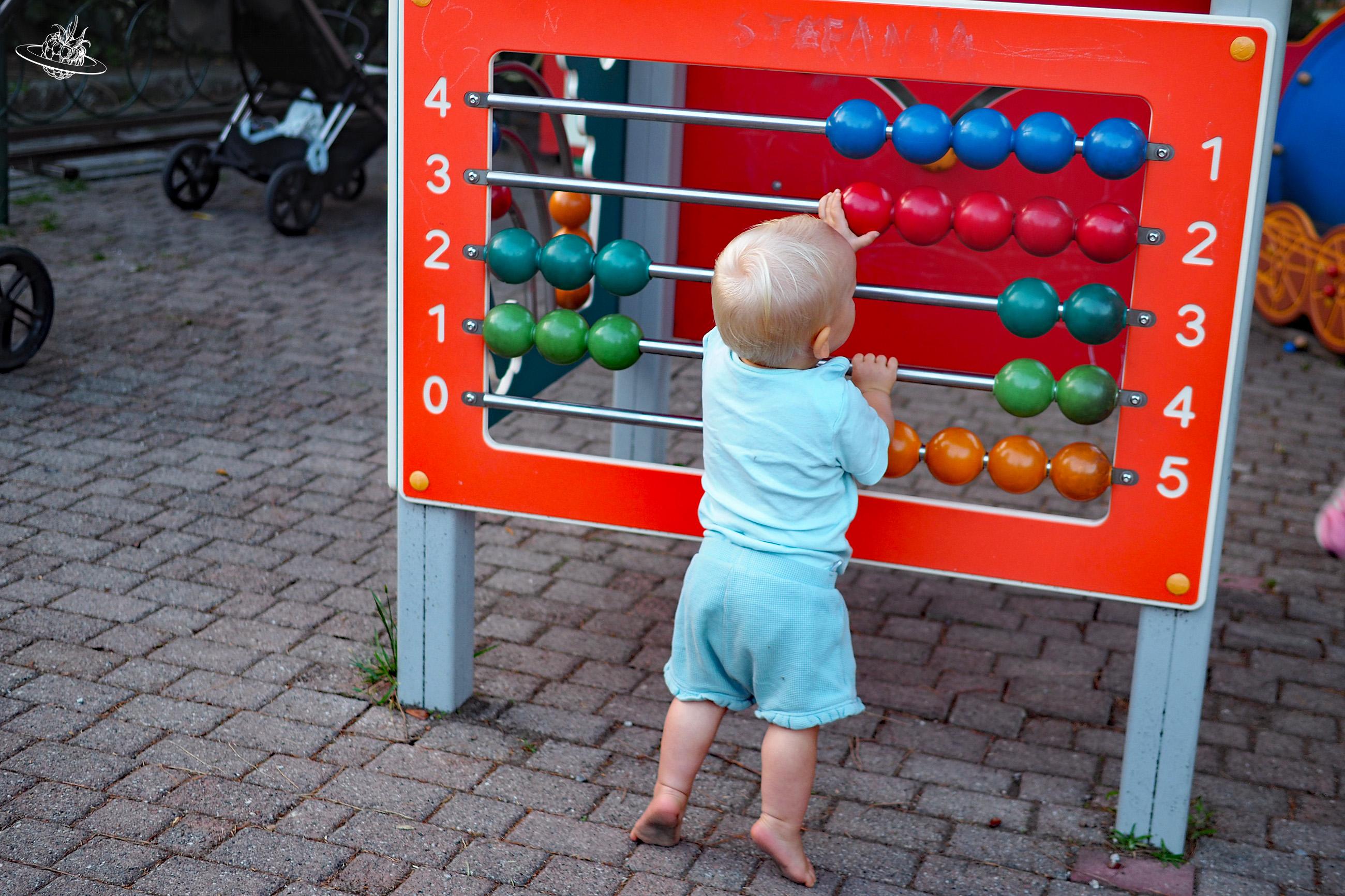 Kind spielt mit Kugeln an einer Wand auf einem Spielplatz